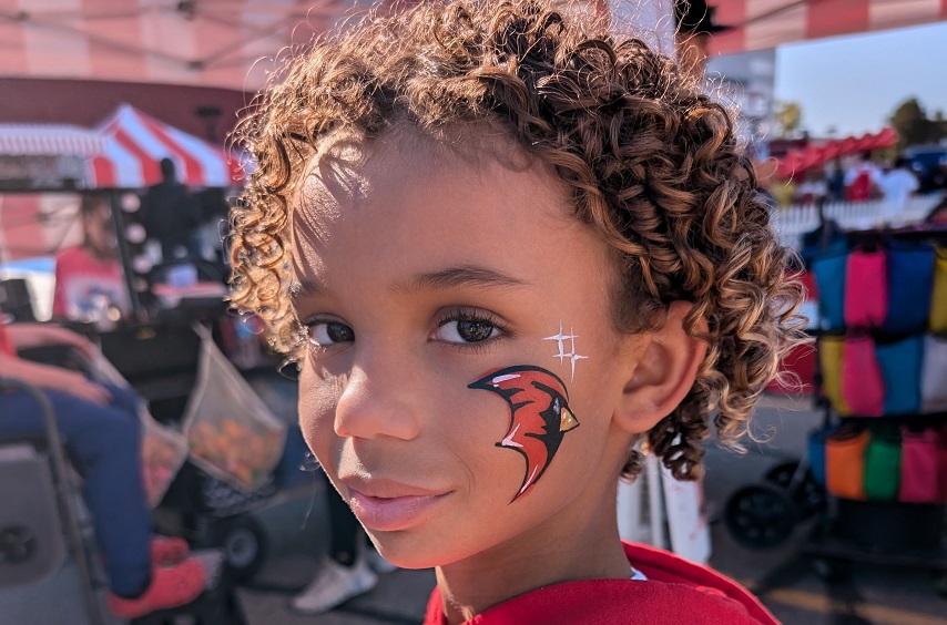 2024 Homecoming. Young child of an alum showing off his cardinal face paint at the Alumni Homecoming Tailgate